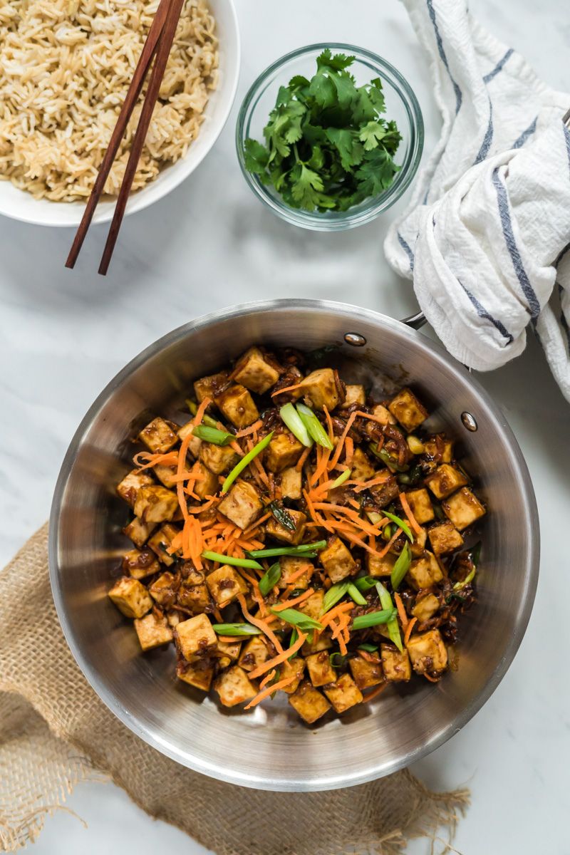 Crispy tofu with Mongolian sauce in a skillet with brown rice and cilantro on the side.