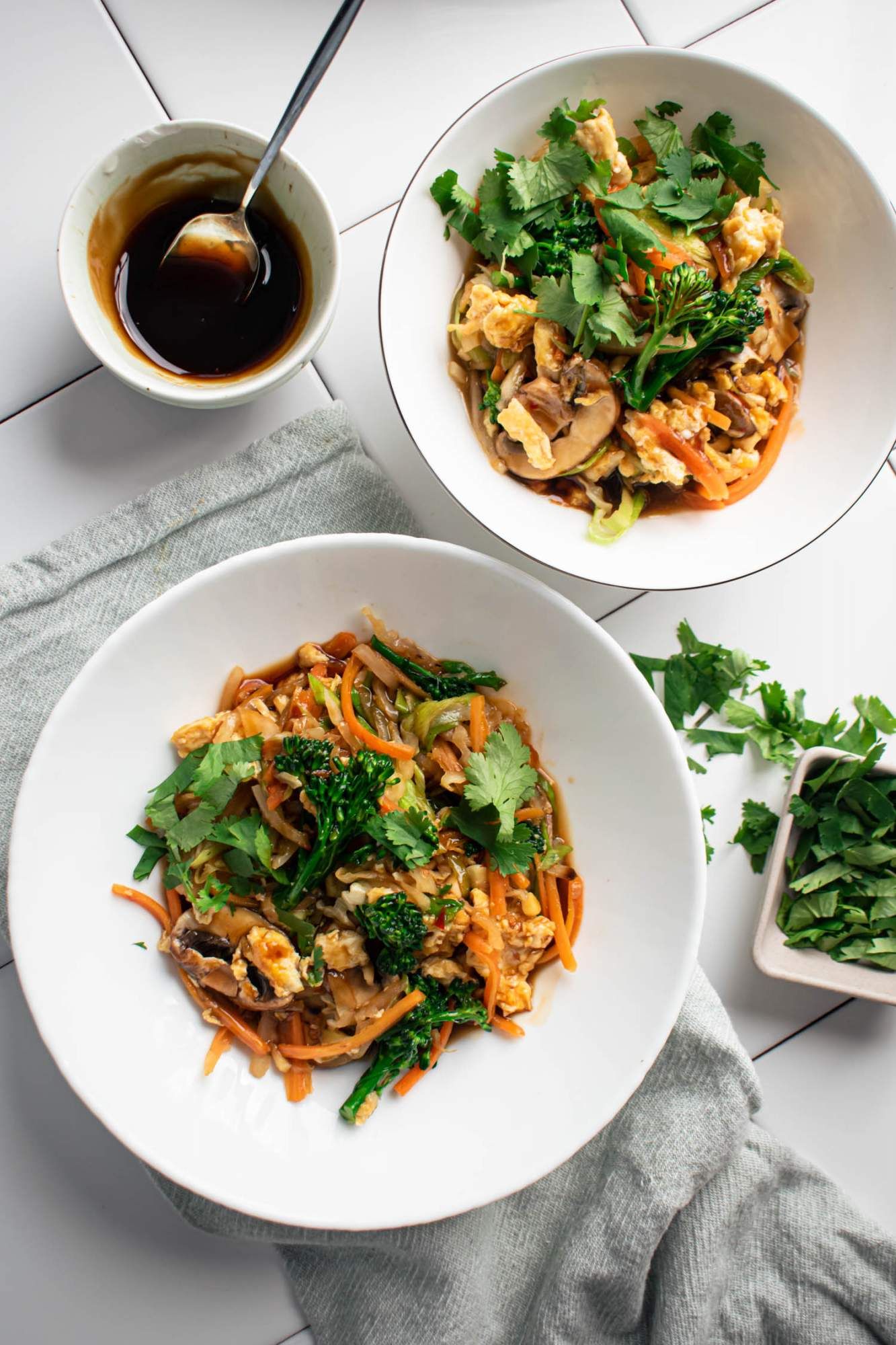 Stir fried Chinese moo shu vegetables with cabbage, broccoli, mushrooms, and eggs in moo shu sauce in two bowls.