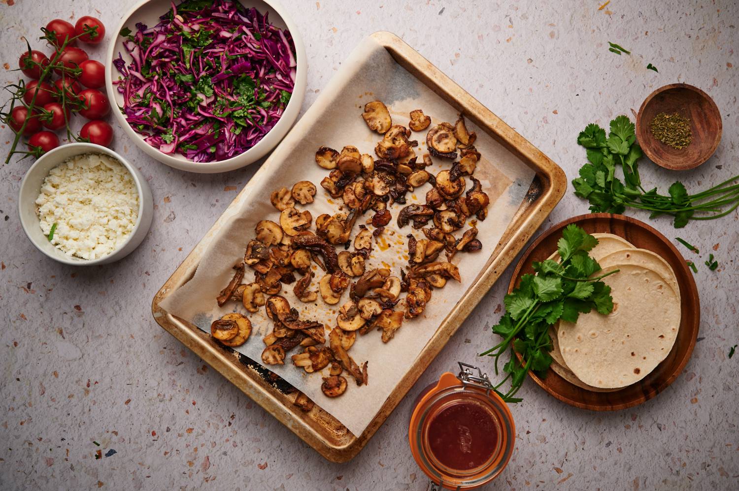 Crispy mushrooms for tacos on a baking sheet with tortillas, cabbage slaw, cheese, and salsa on the side. 