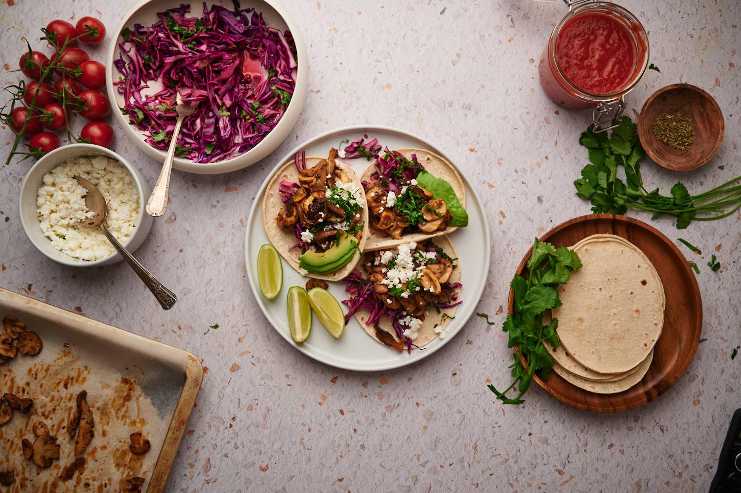 Vegetarian mushroom tacos with limes, roasted mushrooms, corn tortillas, slaw, and tomatoes.