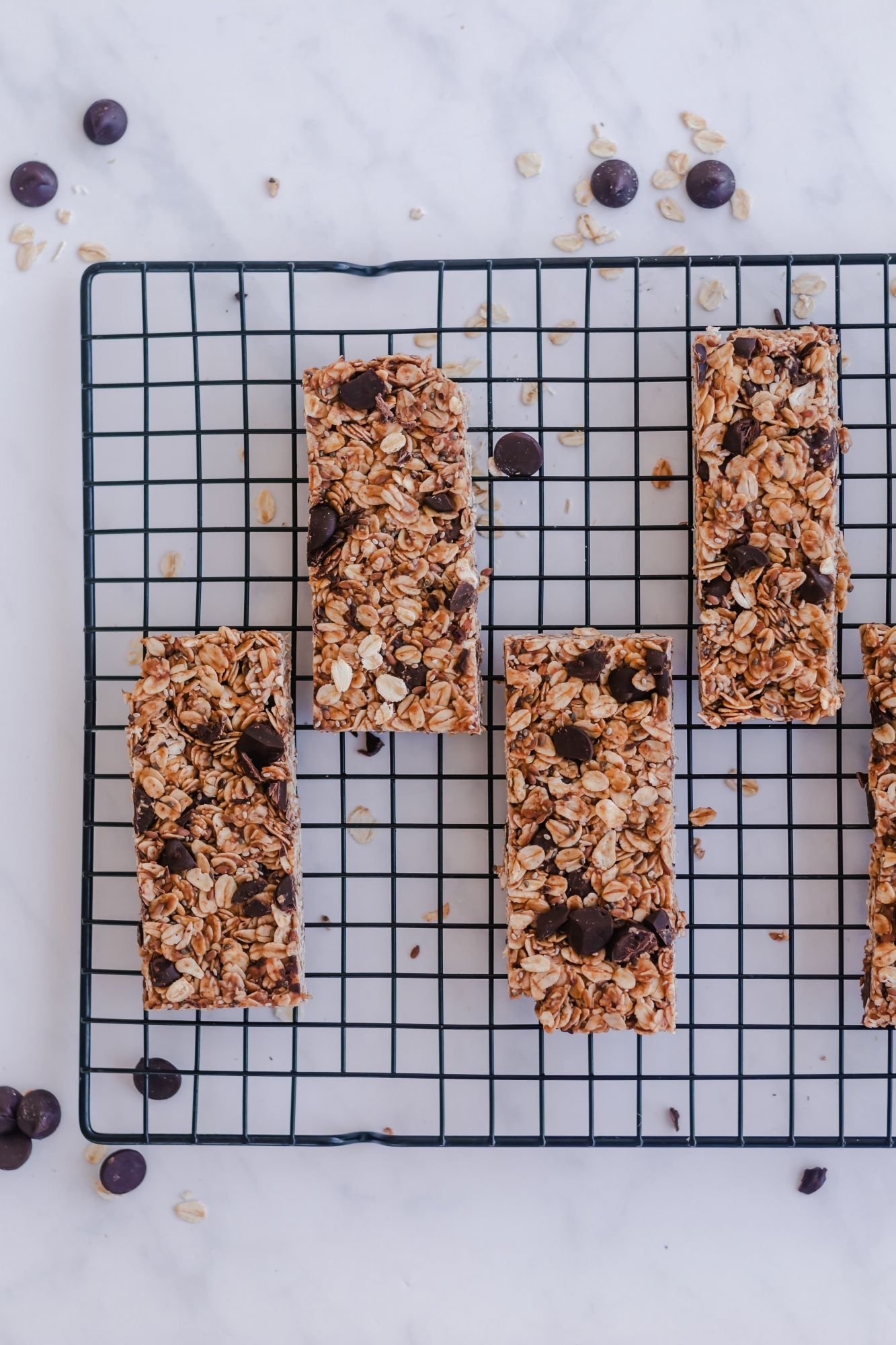 Homemade granola bars with rolled oats, cinnamon, chia seeds, and chocolate chips on a wire rack.