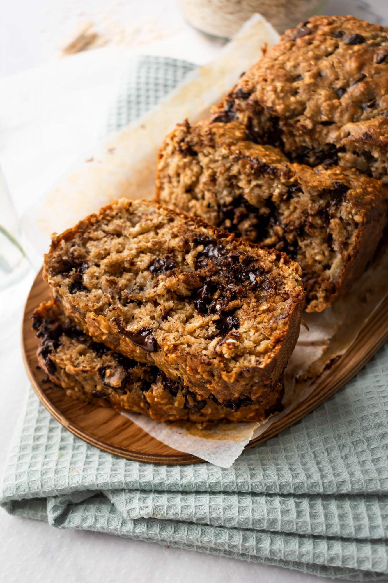 Banana oat bread with semi sweet chocolate chips sliced and served next to a light blue napkin.