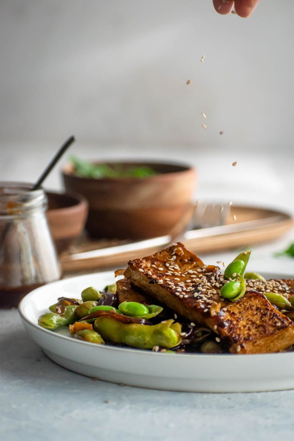 Skillet fried tofu with edamame in Asian marinade with sesame seeds bring sprinkled on top.