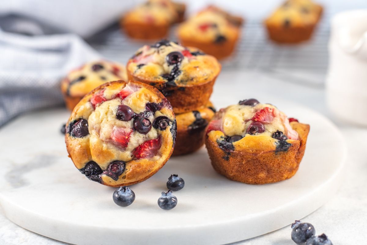 Muffin pancakes with blueberries and strawberries stacked on a marble board.