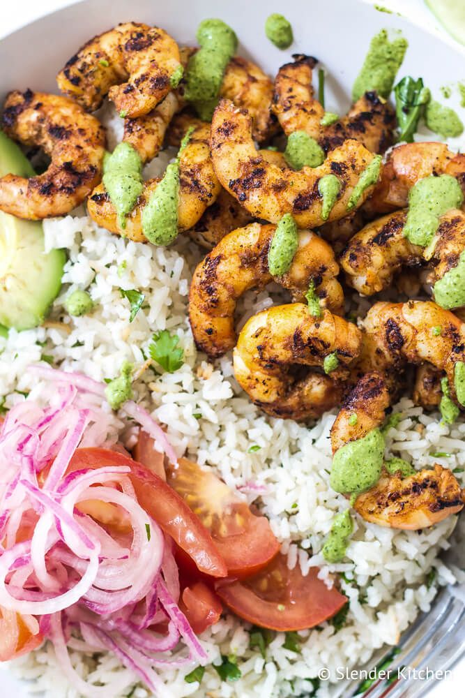 Shrimp bowls over white rice with Peruvian green sauce, red onions, and tomatoes.