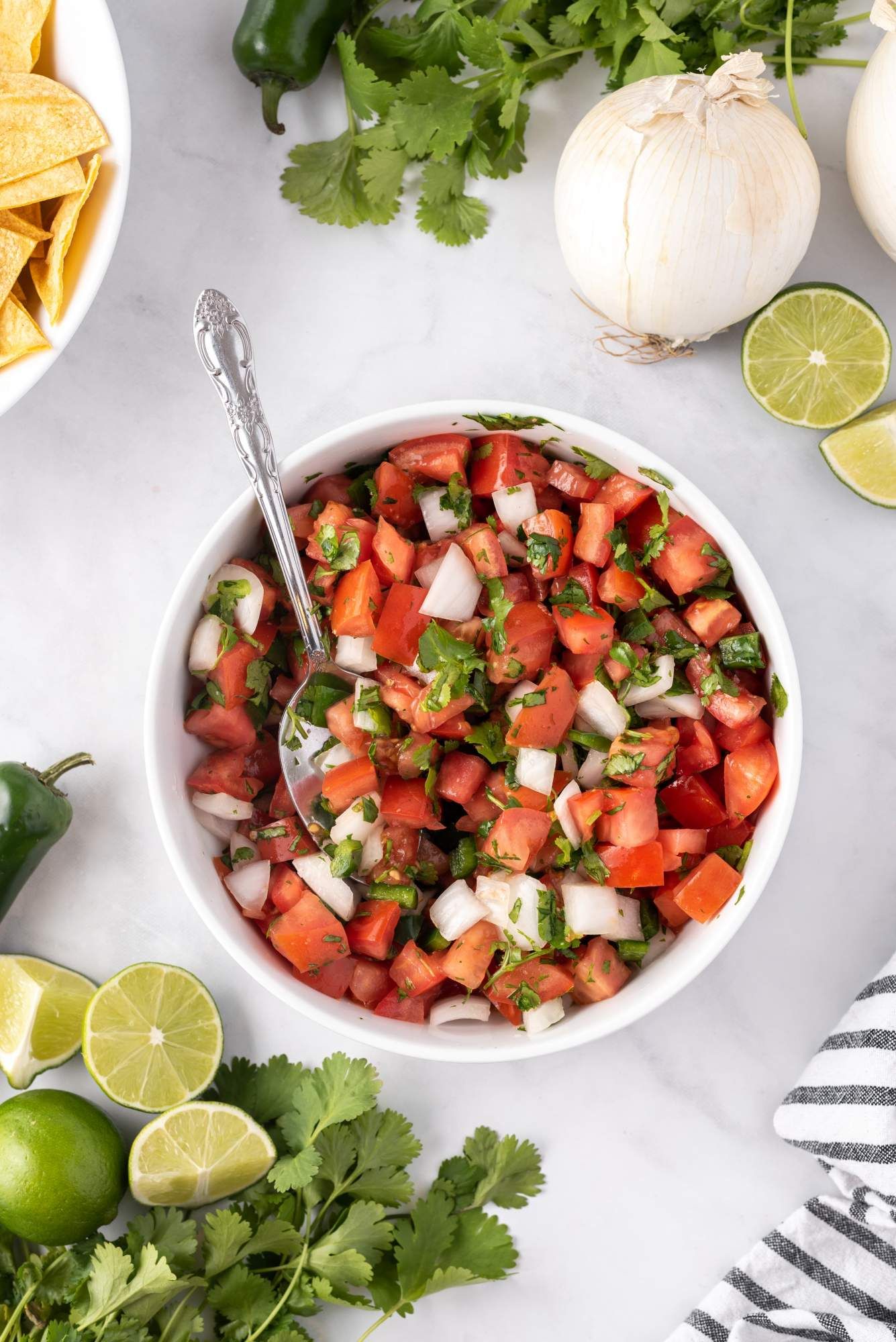 Homemade Mexican pico de gallo served in a bowl with baked tortilla chips.