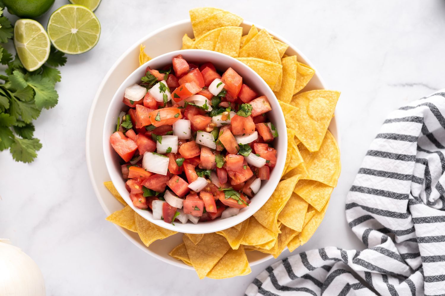 Bowl of pico de gallo with tomatoes, onions, cilantro, and lime juice served with tortilla chips.