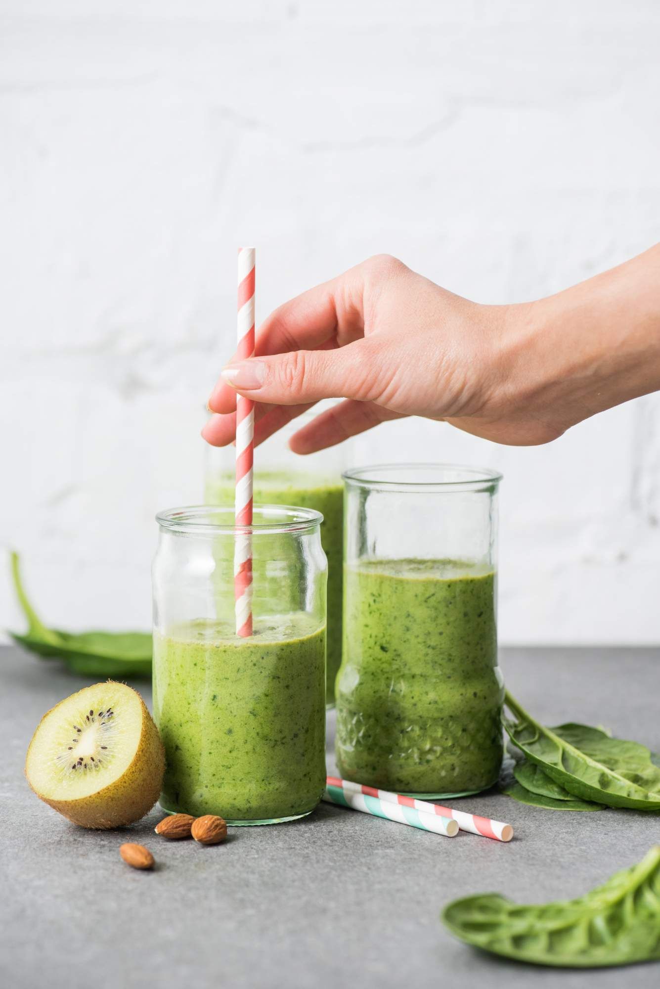 Pineapple smoothie with cucumber, spinach, banana, and kiwi in a glass with a straw.