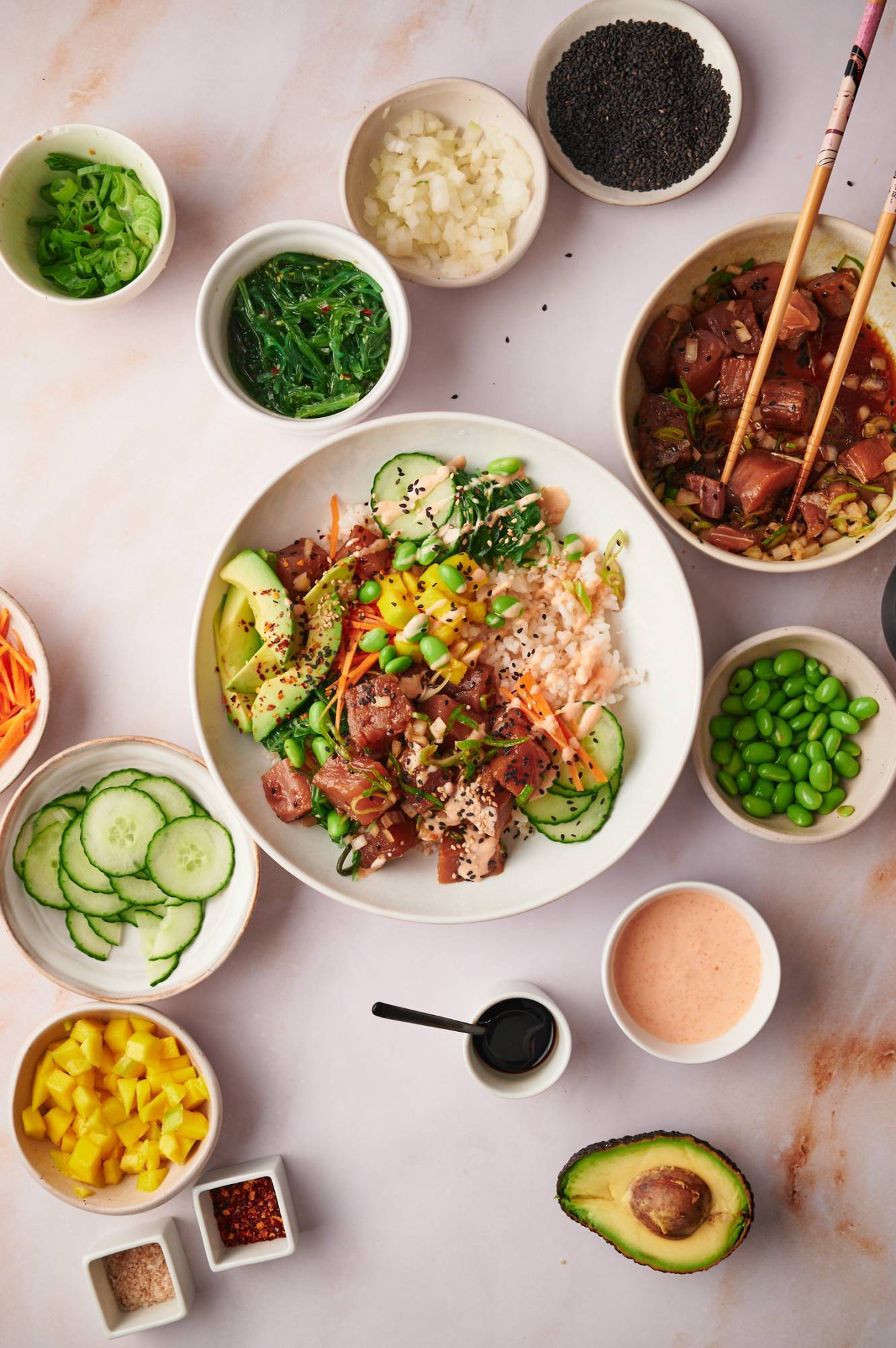 Hawaiian poke bowls with raw tuna, avocado, steamed rice, cucumber, seaweed salad, and green onions.