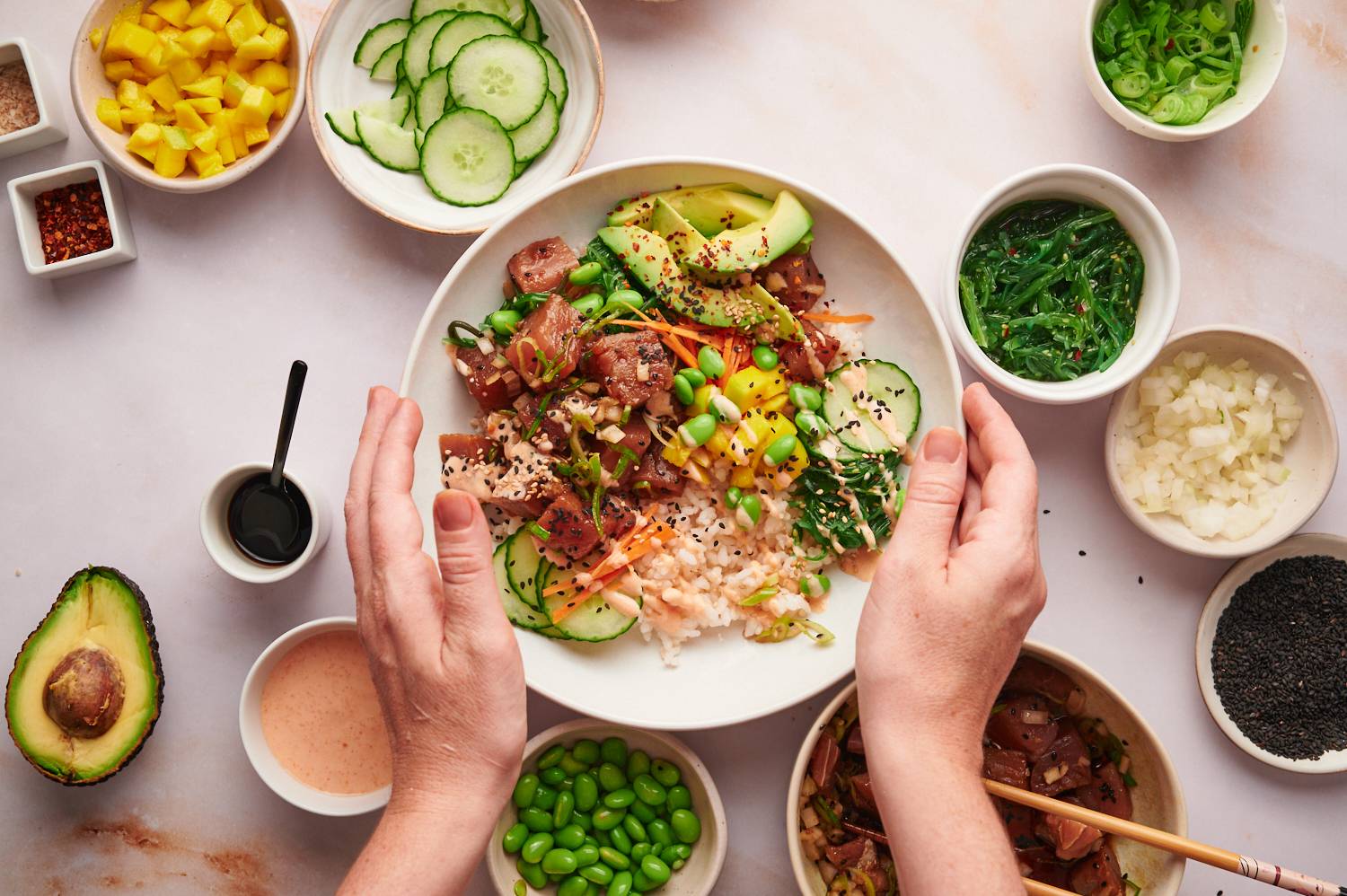 Tuna poke bowls with steamed rice, cucumber, mango, cucumber, avocado, and sesame seeds.