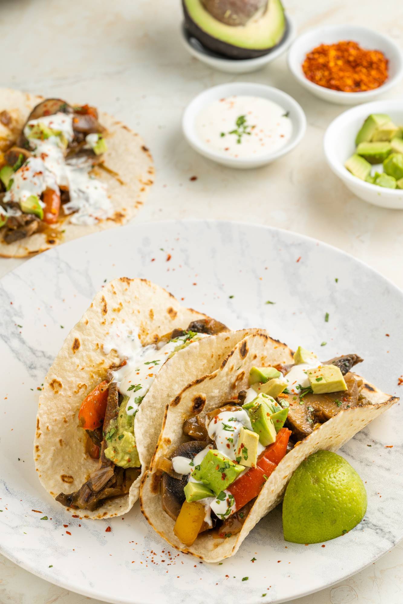 Mushroom fajitas with portobello mushrooms, bell peppers, red onions, cilantro, lime, avocado, and sour cream in warm tortillas.