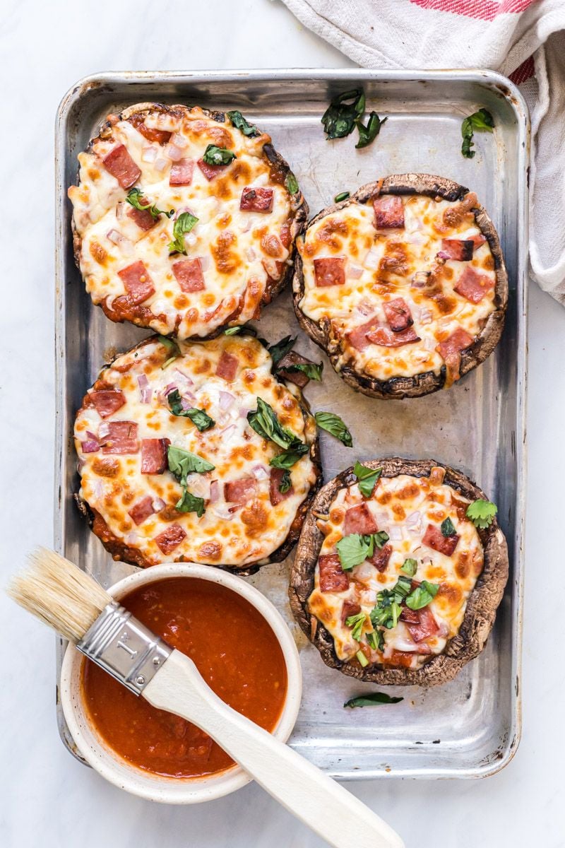 Easy portobello mushroom pizzas with ham, red onion, basil, marinara sauce, and melted cheese on a silver baking sheet.