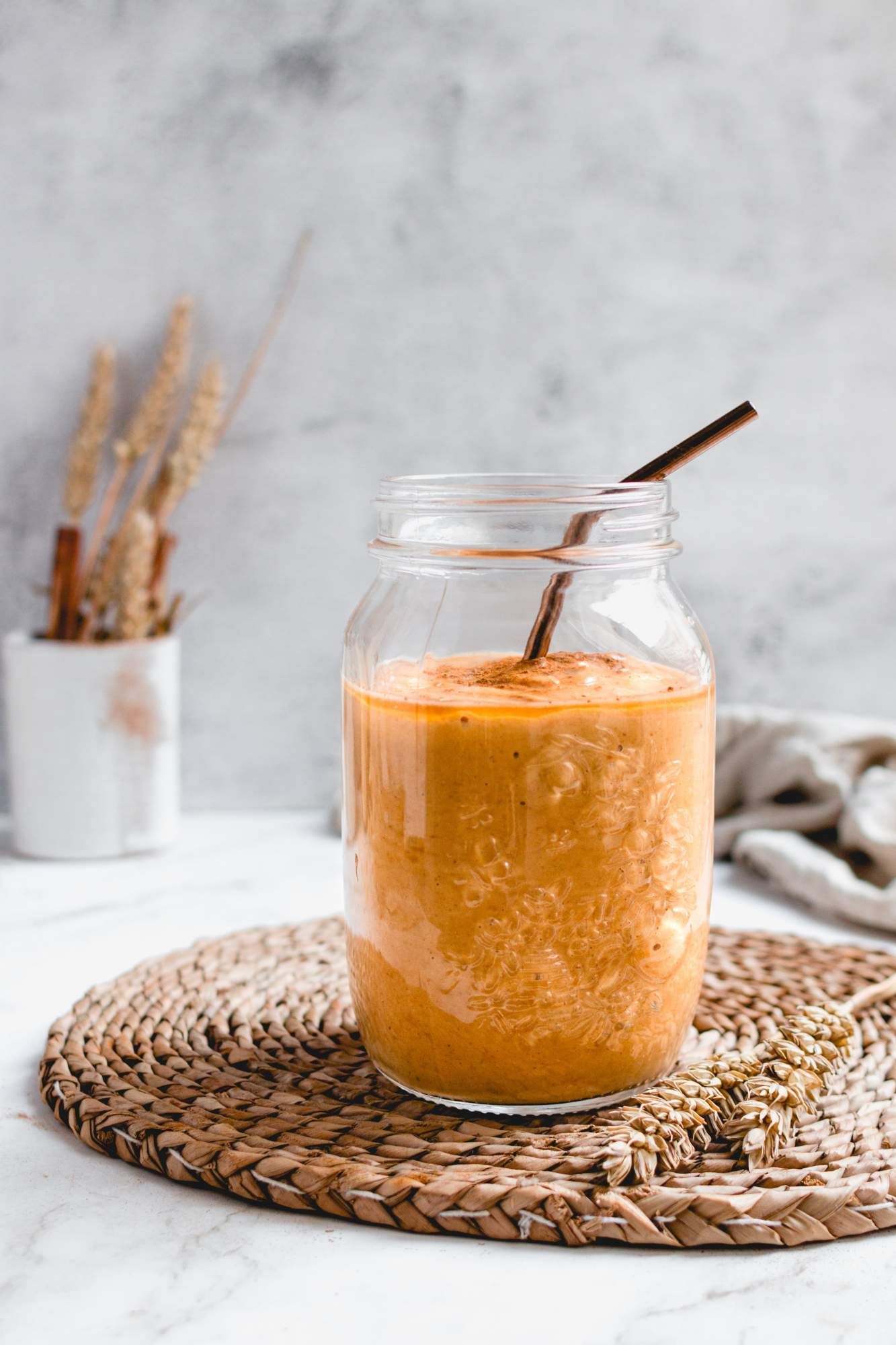 Pumpkin spice smoothie with pumpkin and oats in a glass mason jar with a straw.