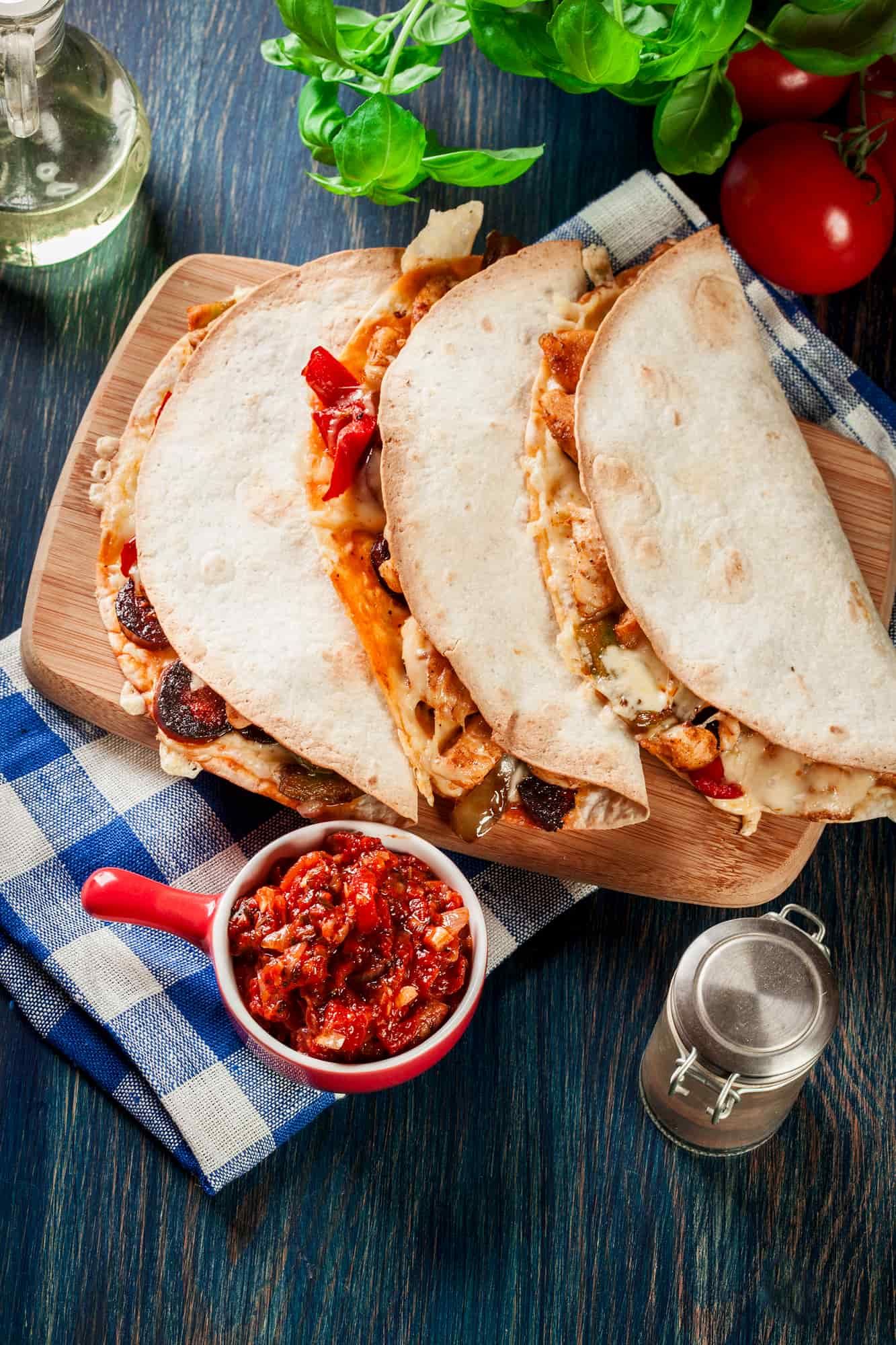 How to make a folded quesadilla with any fillings and cheese served on a plate with fresh tomatoes.