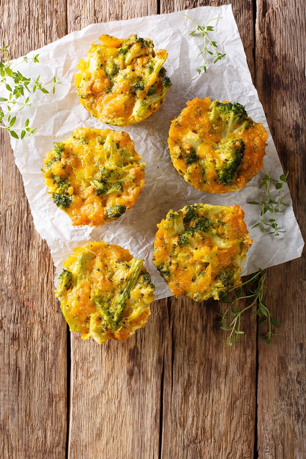 Quiche muffins with turkey and broccoli on parchment paper and a wooden background.