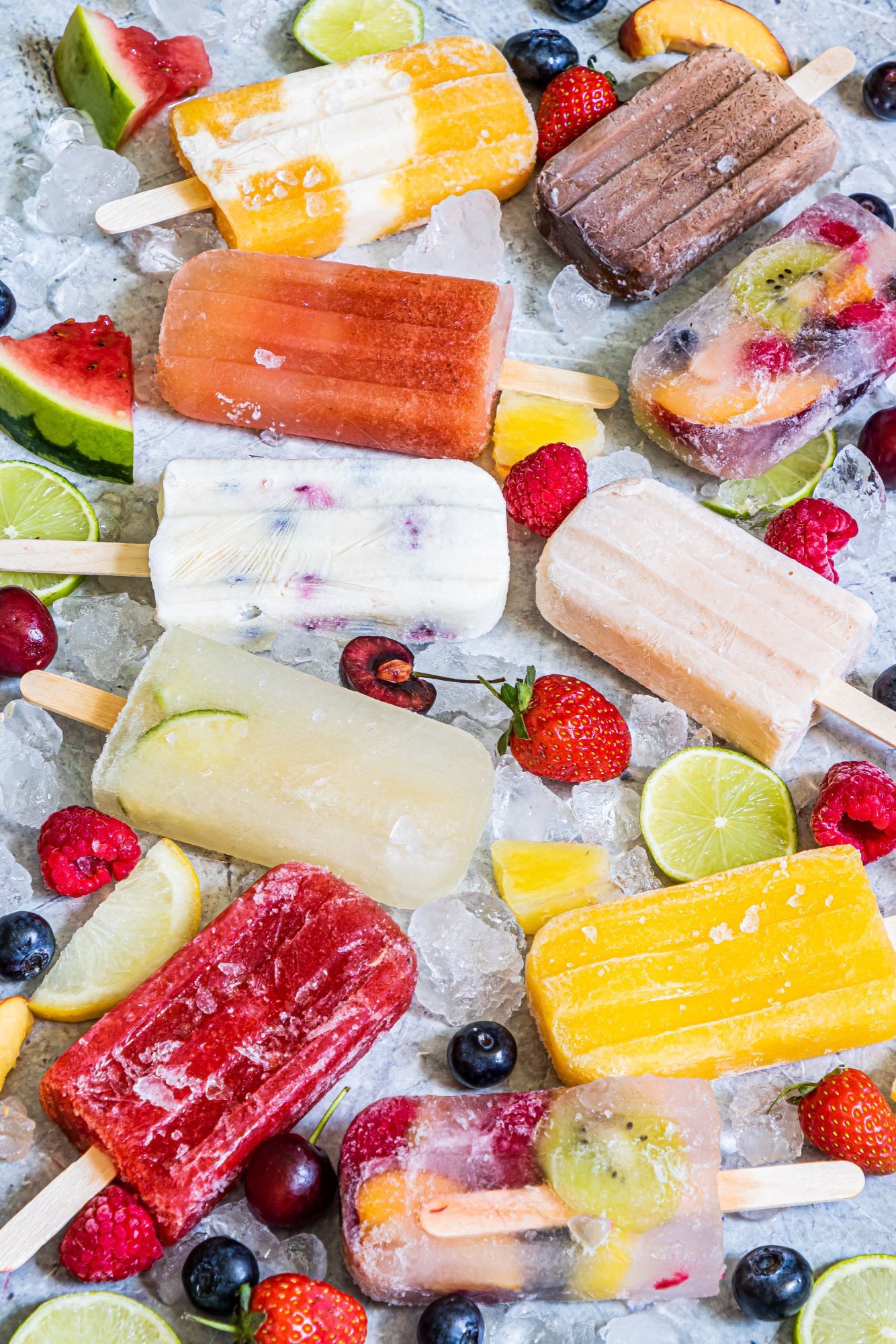 Homemade fresh fruit popsicles and creamy fruit popsicles on a tray with ice.