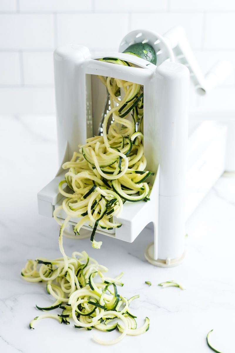 Zucchini noodles being made with a spiralizer.