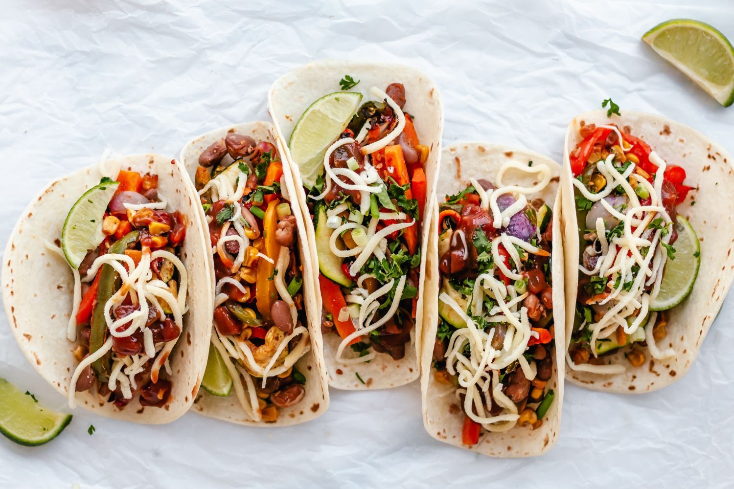 Roasted vegetable fajitas topped with salsa, beans, shredded cheese, and cilantro on flour tortillas.