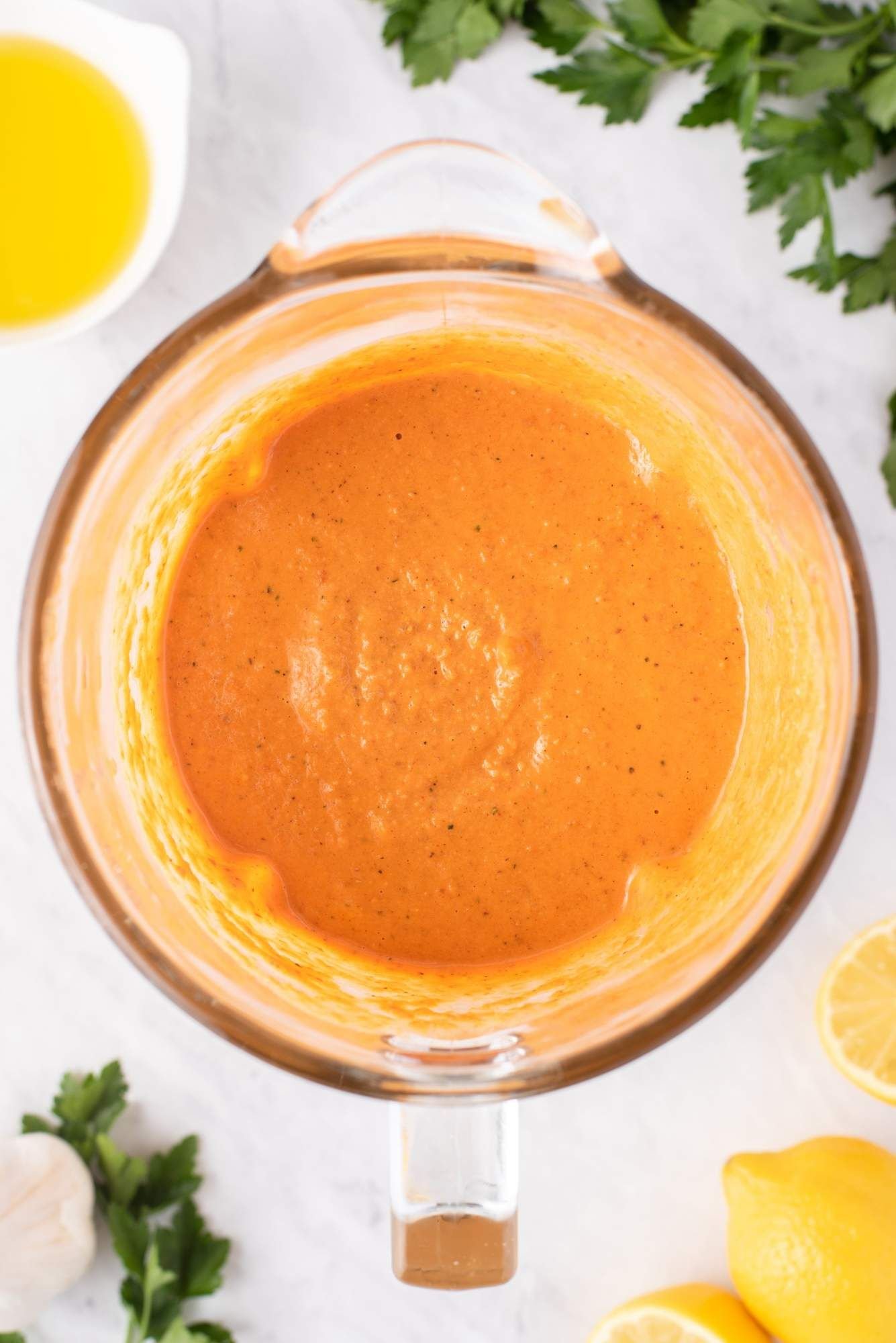 Spinach romesco sauce in a blender with almonds, garlic, parsley, and tomatoes in a blender.