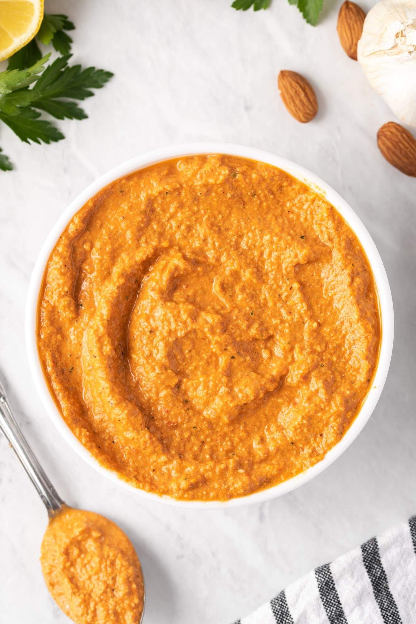 Creamy Romesco sauce in a white bowl with blended almonds, tomatoes, red pepper, garlic, and olive oil.