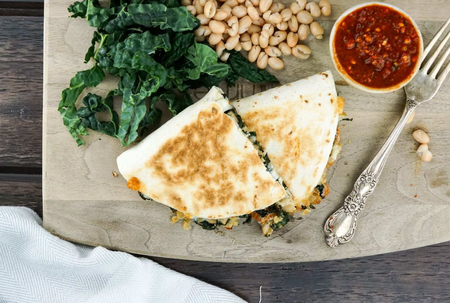 Rosemary White Bean and Kale Quesadilla on cutting board with kale and white beans.