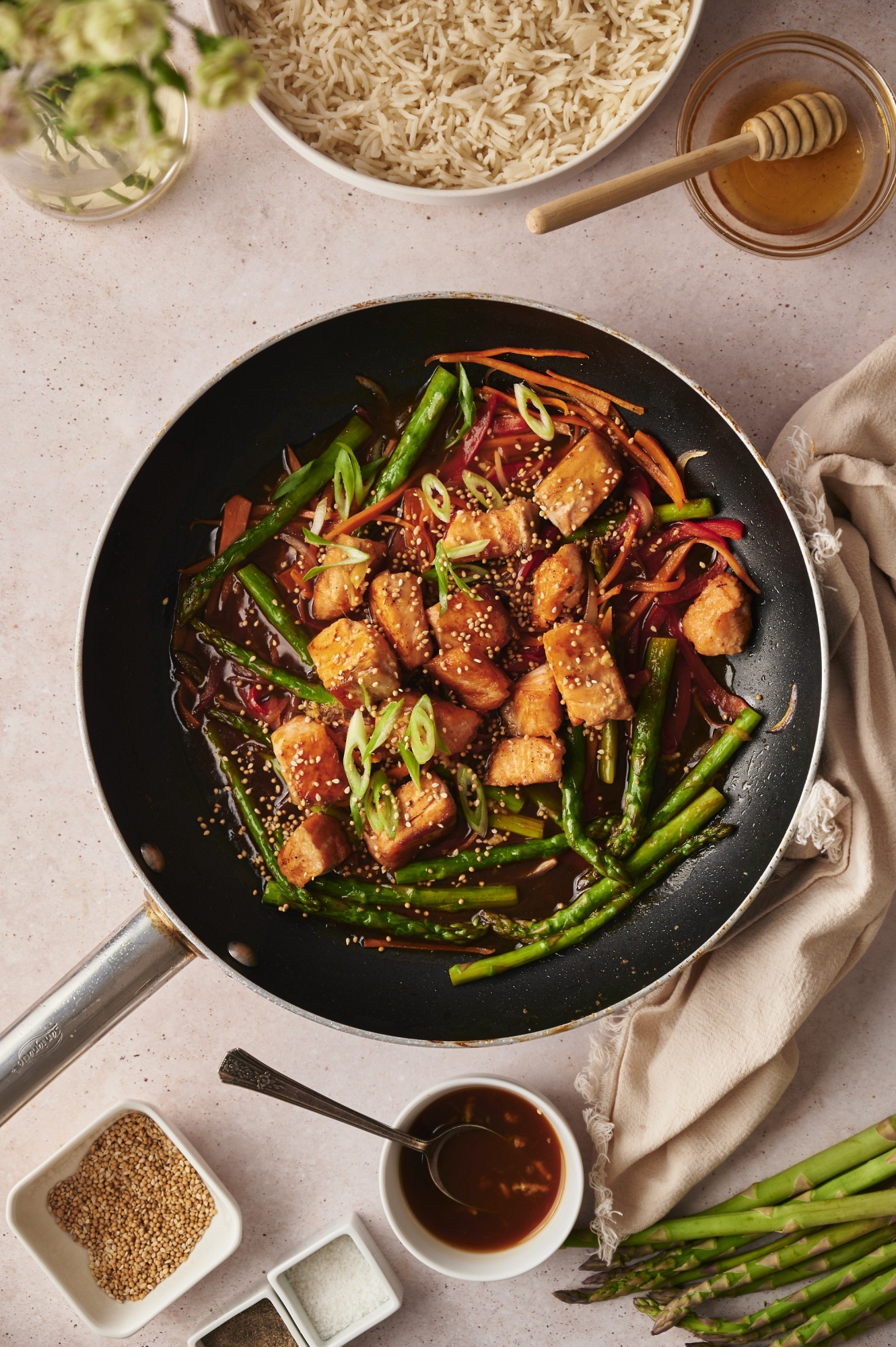 Stir fried salmon with asparagus, red peppers, and carrots in teriyaki sauce served with sesame seeds and green onions.