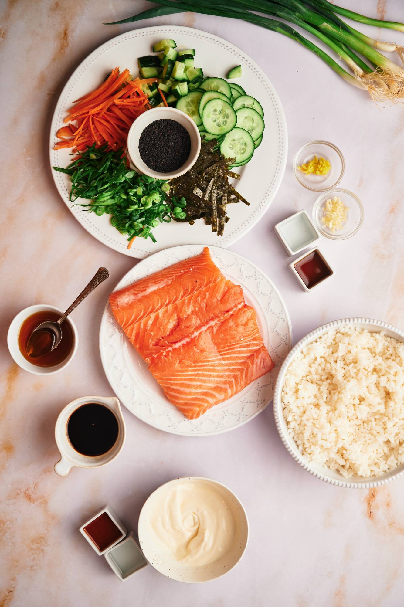 Ingredients for homemade salmon sushi bowls with rice, salmon, seaweed, vegetables, and spicy mayo. 