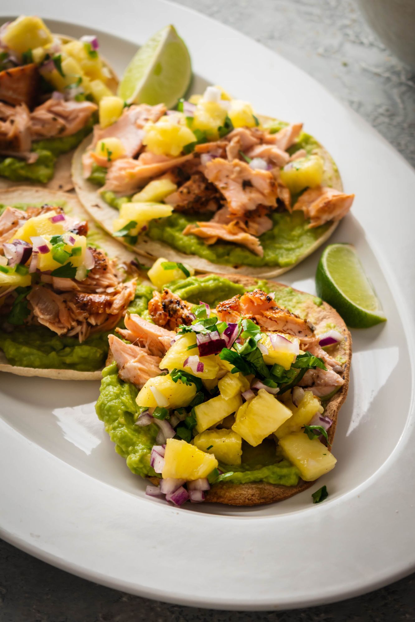 Mexican salmon tostadas with spice coated salmon on a corn tortilla with avocado and pineapple salsa.