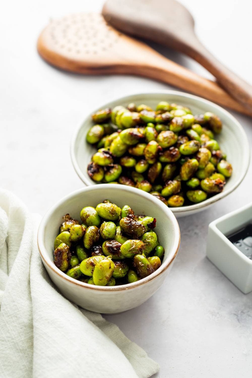 Sauteed edamame with garlic, sesame oil, and black pepper served in a bowl.