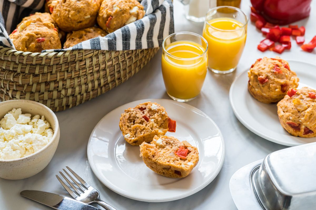 Savory cheese muffins with feta cheese and red peppers served on a plate with juice on the side.