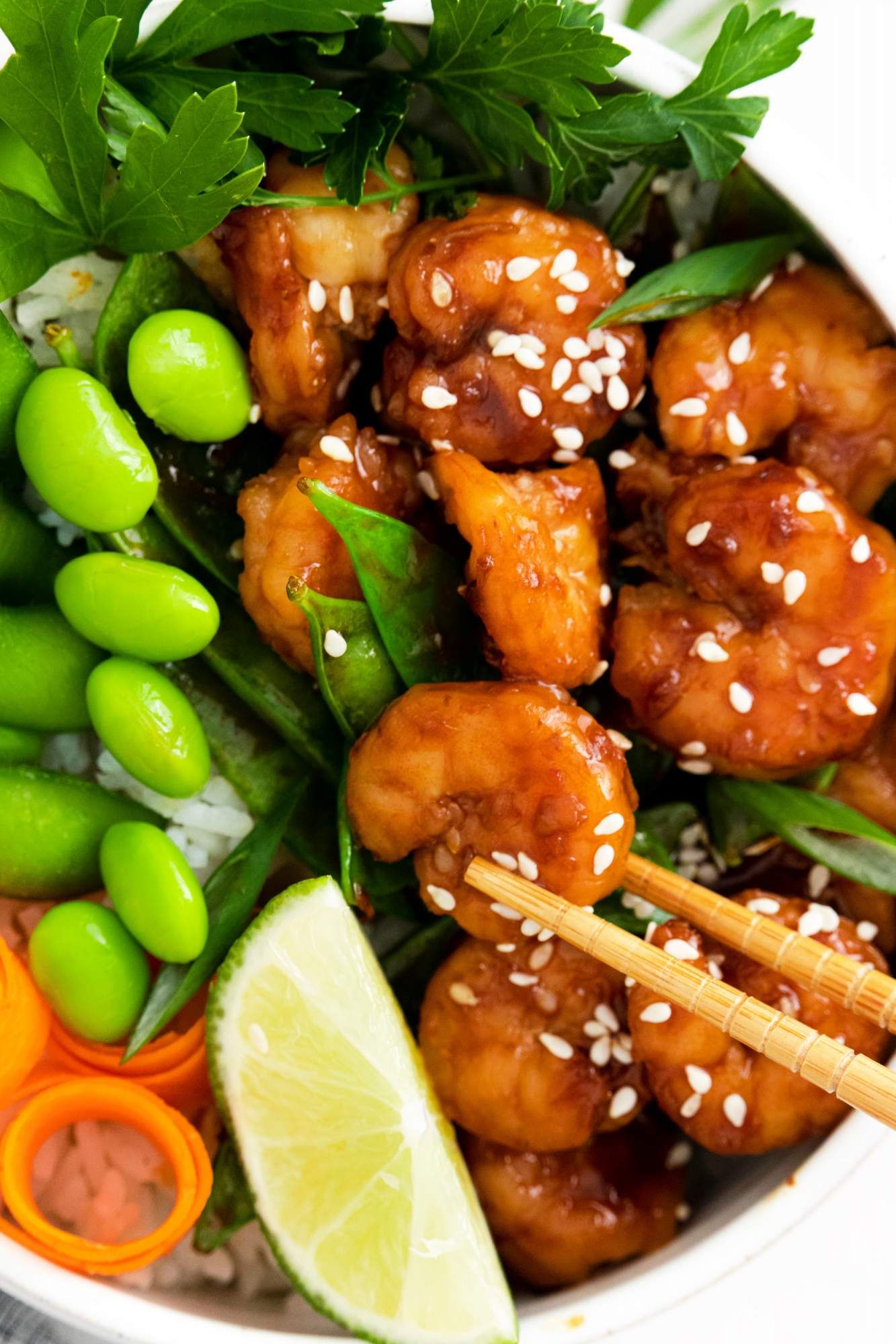 Asian shrimp bowls with sesame shrimp, carrots, rice, edamame, and snow peas.