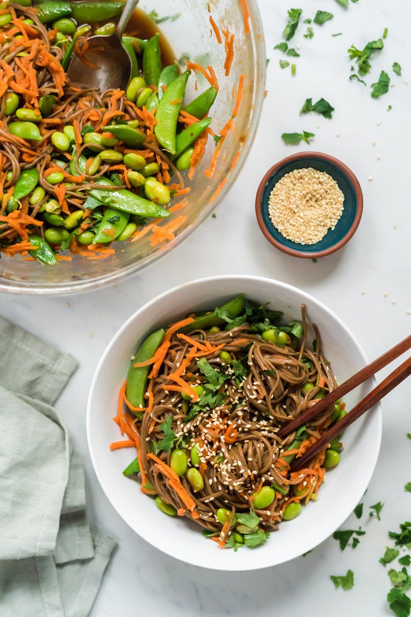 Asian Bowl with noodles, sesame dressing with sugar snap peas, carrots, and edamame in a bowl and chopsticks.