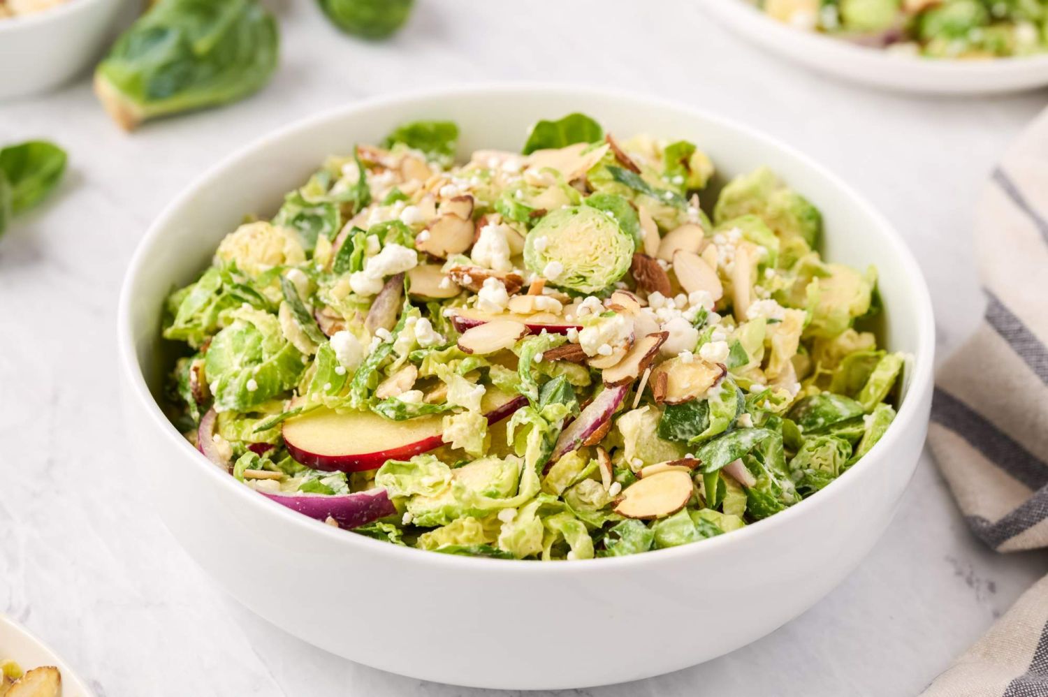 Brussel sprout salad with shaved sprouts, almonds, apples, and red onion and in a creamy dijon dressing,