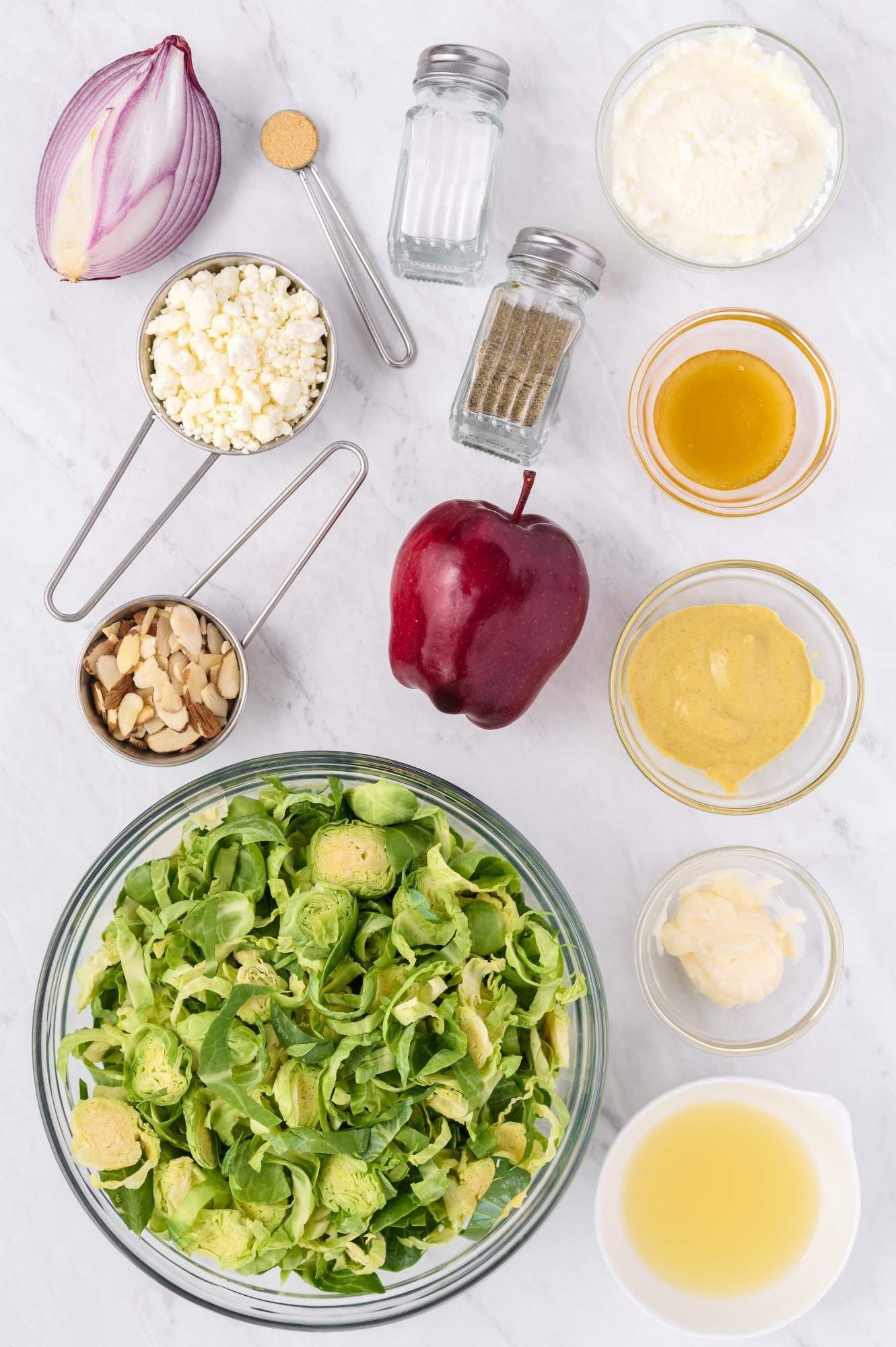 Ingredients for shaved brussels sprouts salad with apples, goat cheese, sliced almonds, and Dijon mustard.