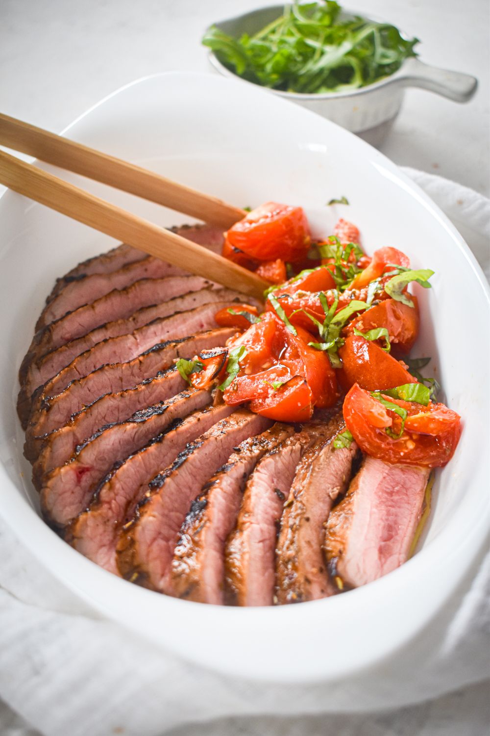 Flank steak with balsamic marinade and tomatoes sliced and served in a whole dish.