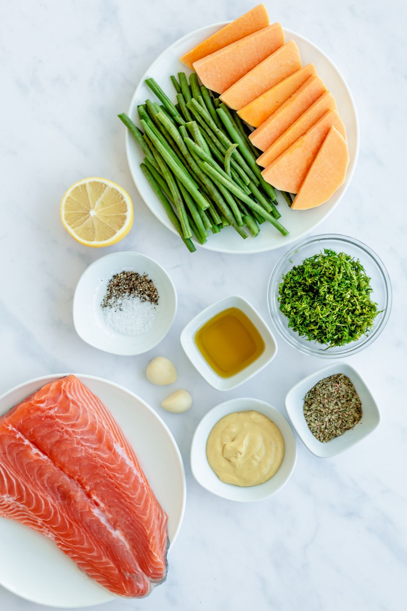 Ingredients for sheet pan salmon including butternut squash, salmon, green beans, herbs, and spices.