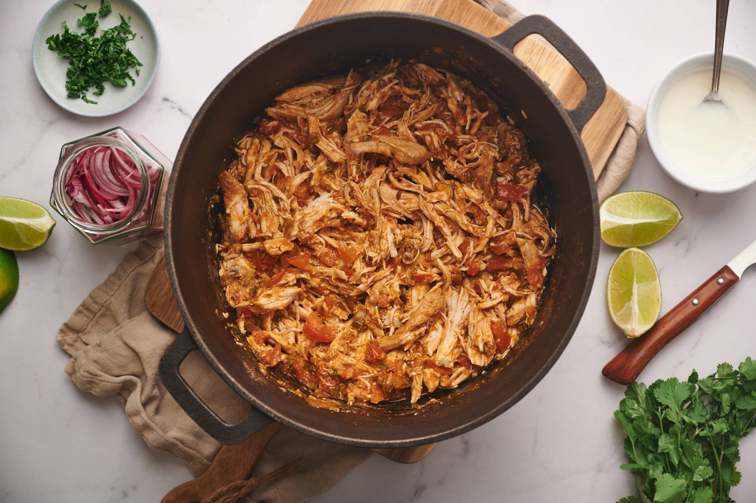 Mexican chicken shredded with tomatoes and spices in a large pot. 