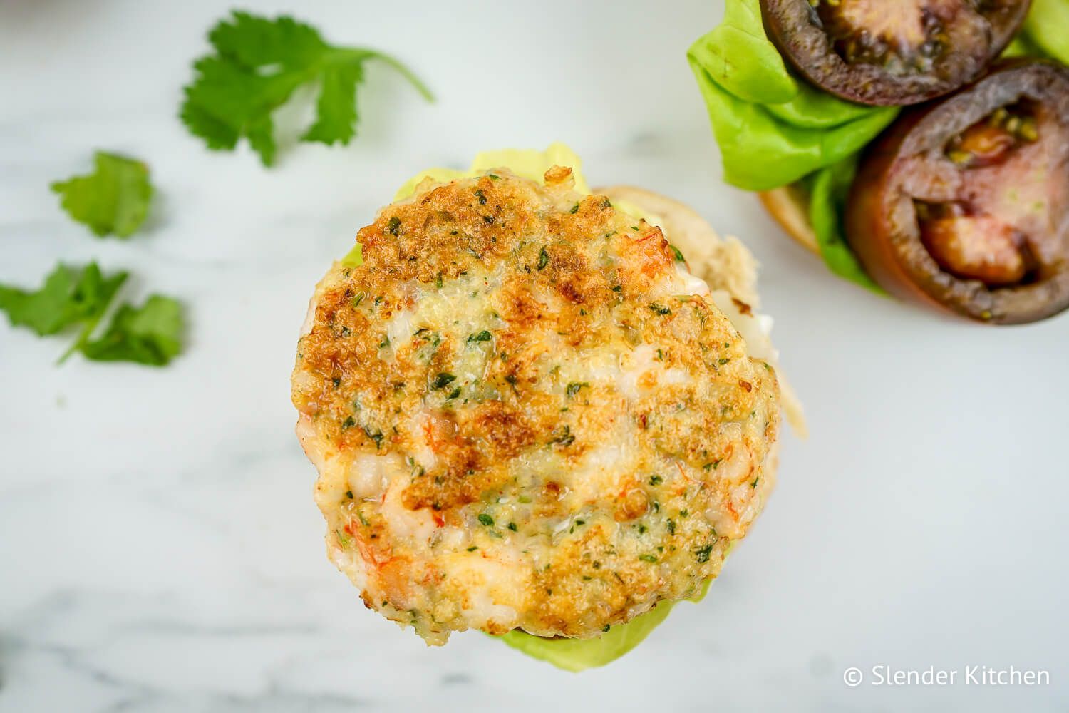 Shrimp burgers with cilantro, breadcrumbs, and garlic on a piece of lettuce.