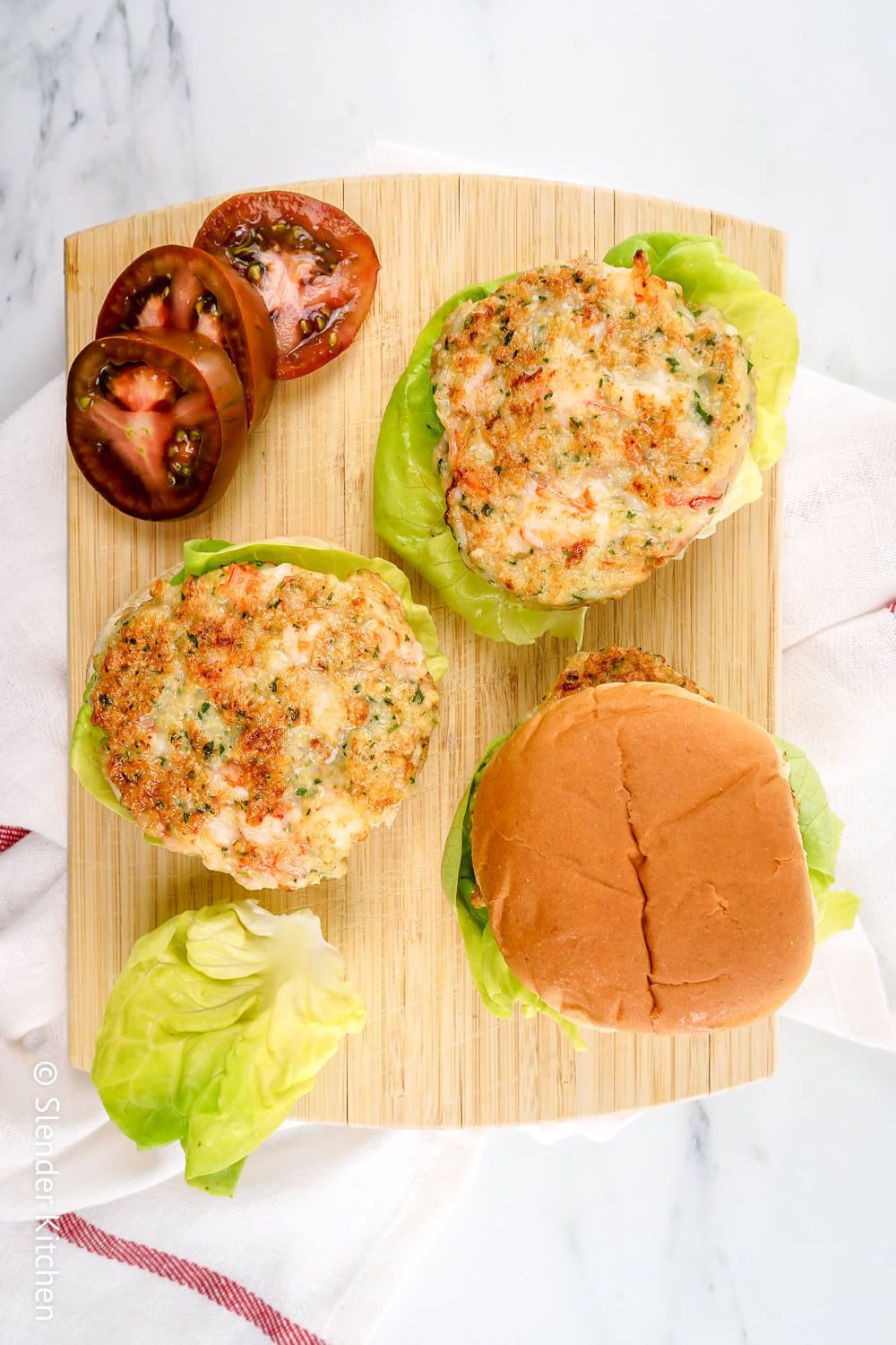 Shrimp burgers with cilantro served open faced with lettuce and tomato.