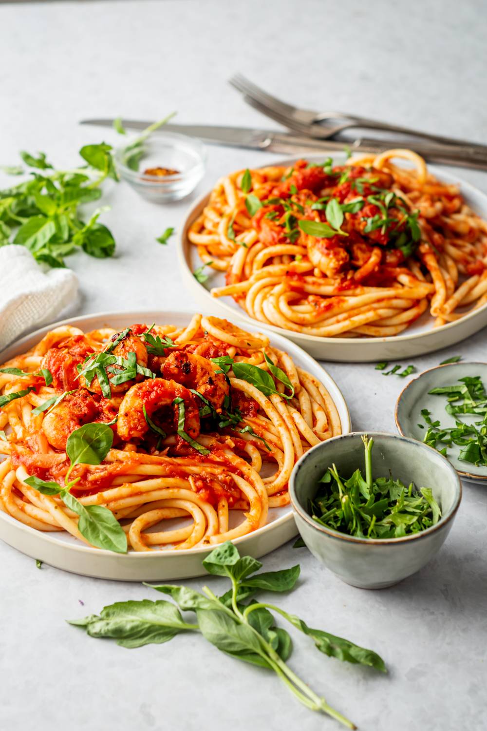 Pasta with shrimp fra diavolo, basil, and parsley served on two plates.