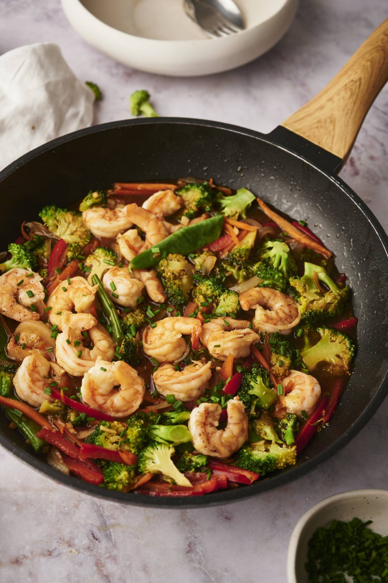 Stir fried shrimp and vegetables in a skillet with homemade stir fry sauce and green onions.