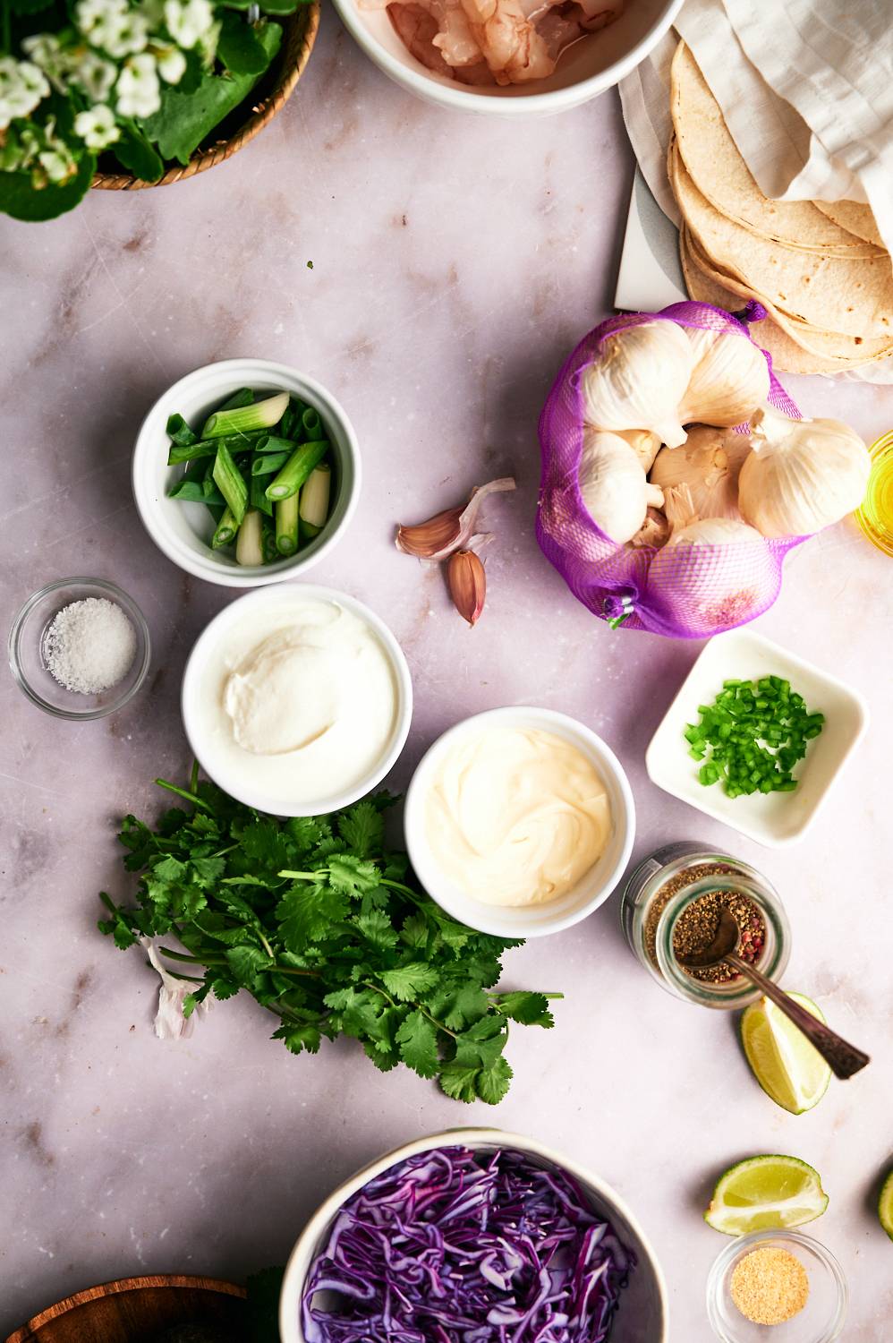 Ingredients for shrimp taco sauce including yogurt, sour cream, garlic, green onion, jalapeno, and lime wedges.