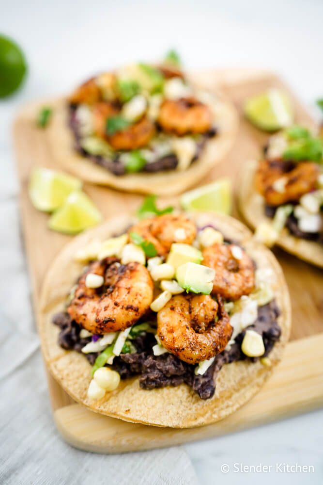 Shrimp tostadas with black beans, cabbage slaw, corn, and avocado on a crispy baked tortilla.