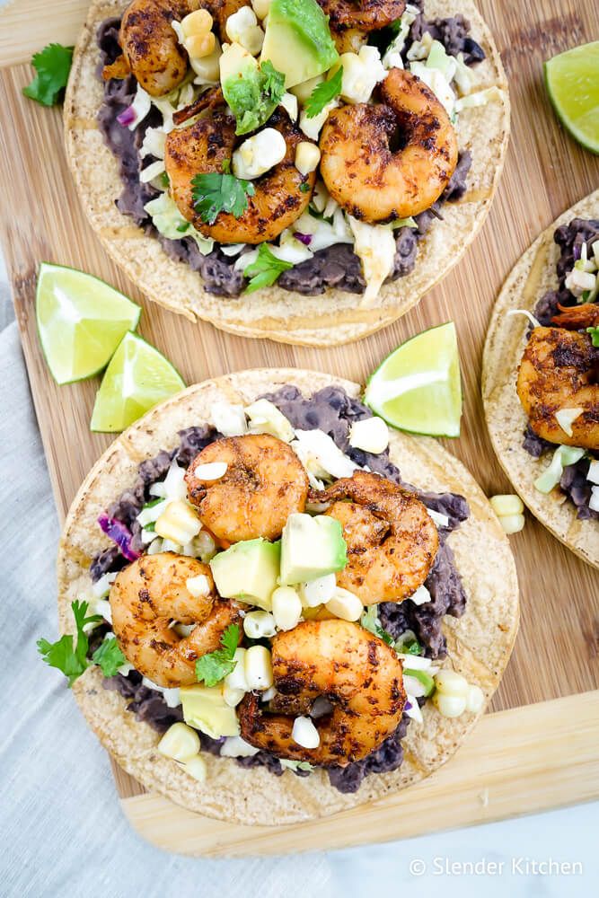 Tostadas with shrimp, beans, corn, slaw, and avocado on corn tortillas.