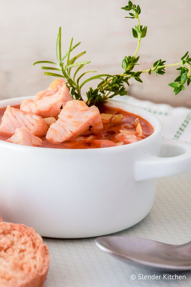 Simple fish stew with carrots, celery, onions, and garlic in a bowl with a napkin on the side.