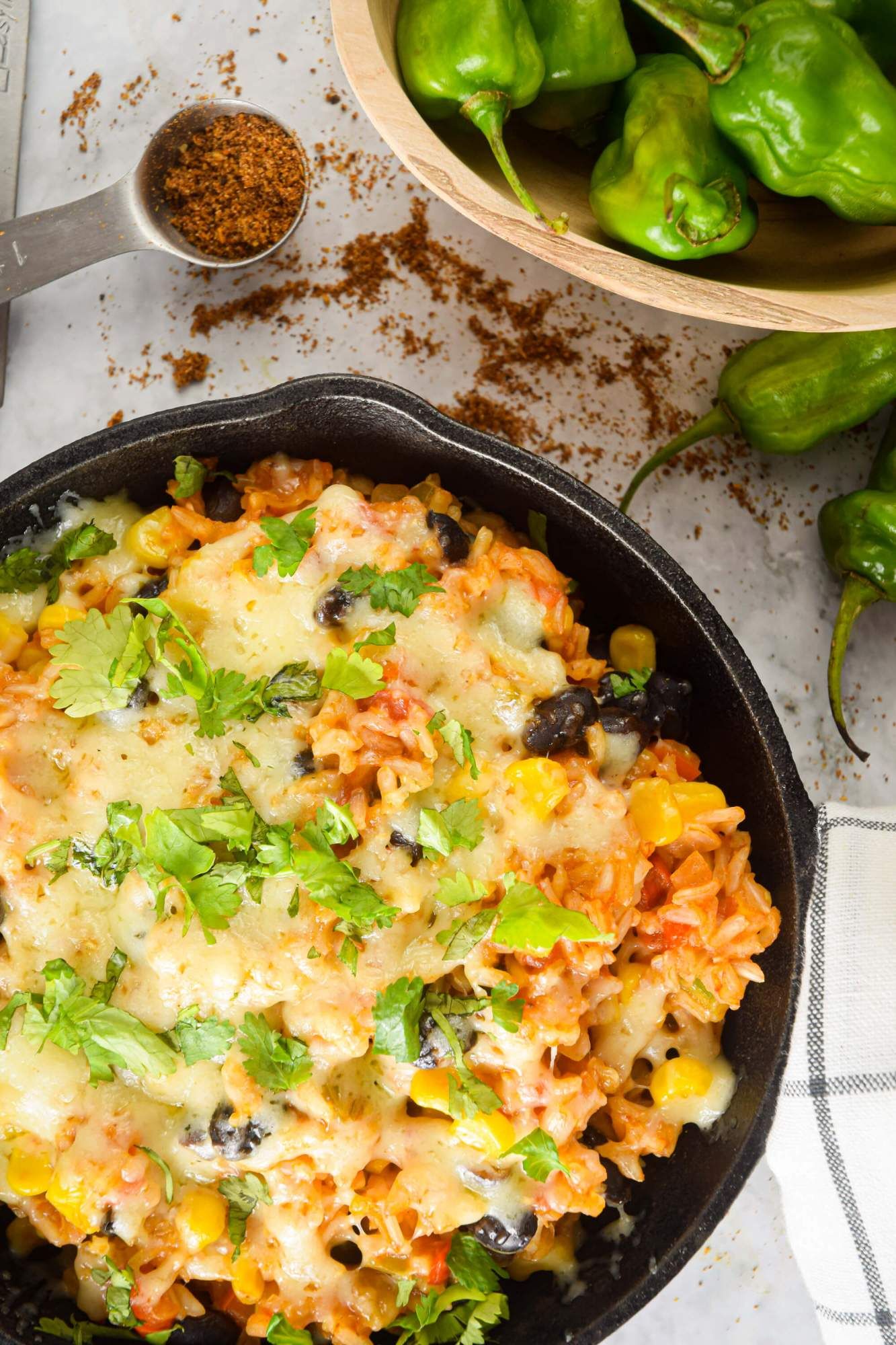 Mexican rice casserole with beans, tomatoes, veggies, and melted cheese with taco seasoning and peppers.