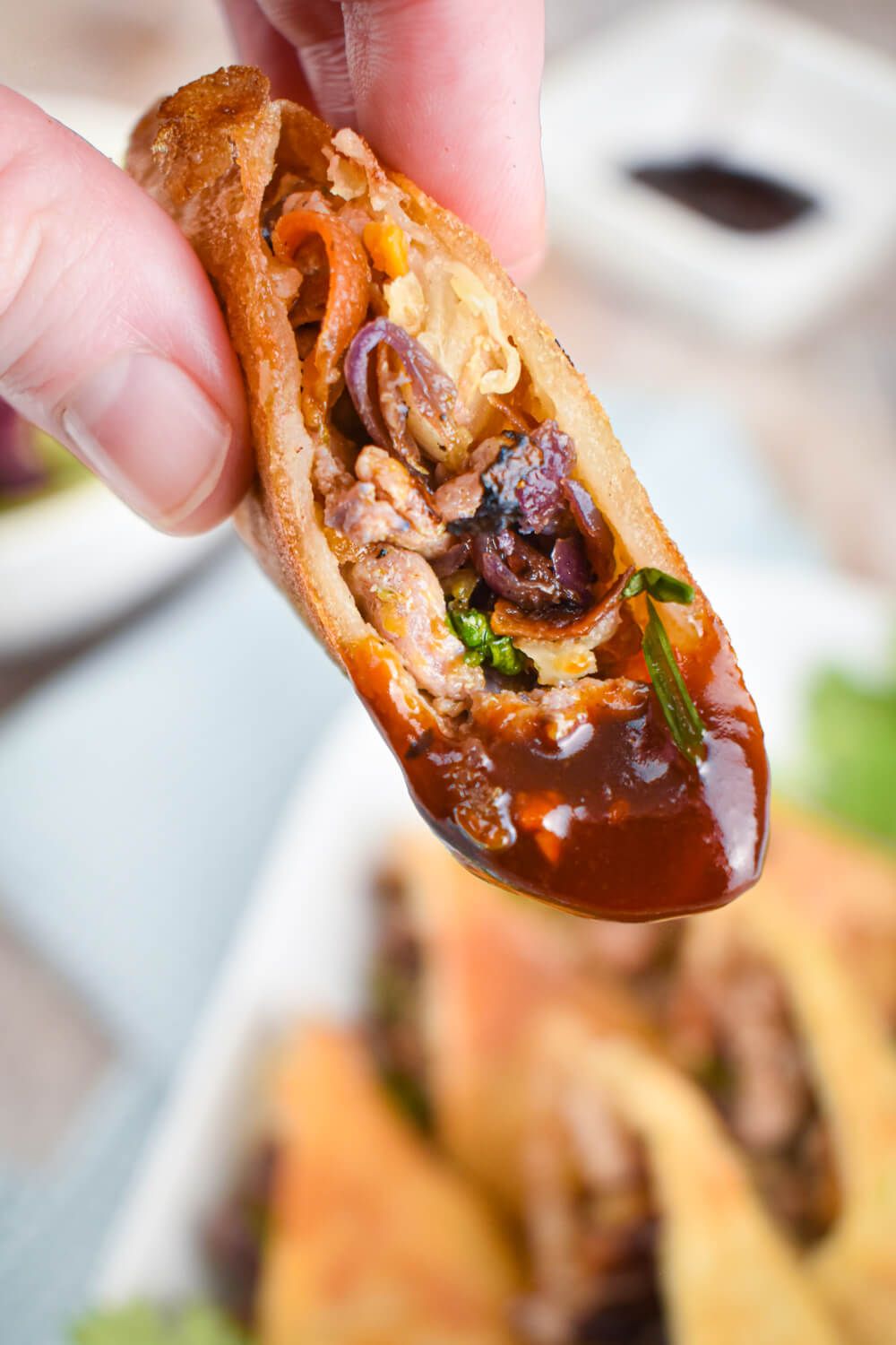 Baked egg rolls cut in half being dipped in oyster sauce.