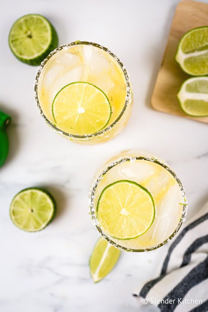 Fresh margaritas with lime juice, orange juice, tequila, and a salted rim in two glasses.