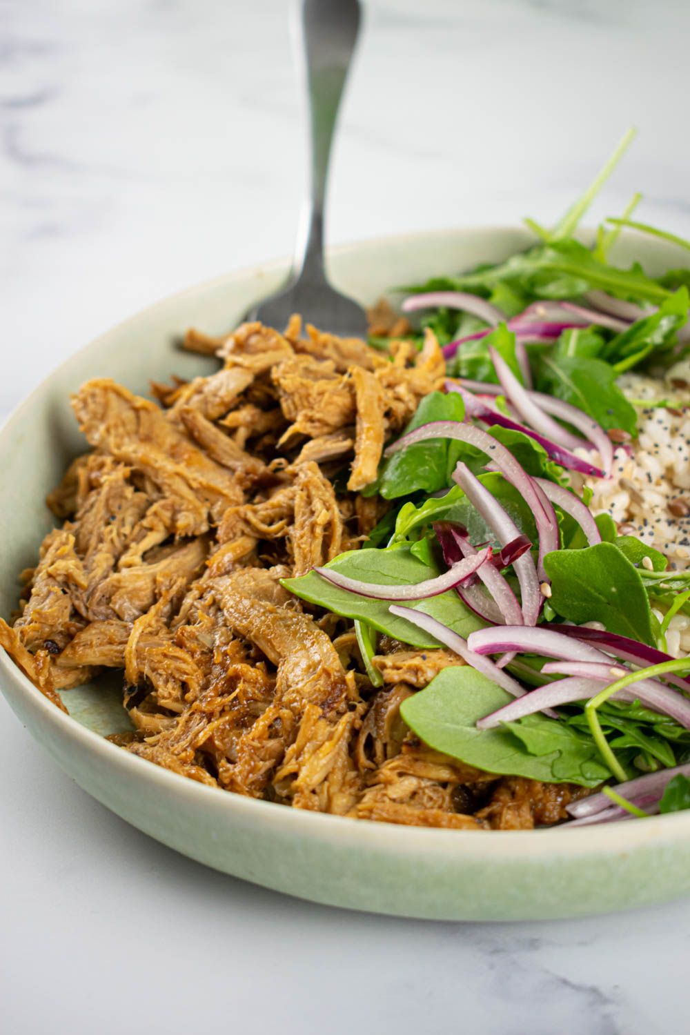 Crockpot Char Siu Pork in a bowl with Chinese barbecue sauce, spinach, rice, and red onions.