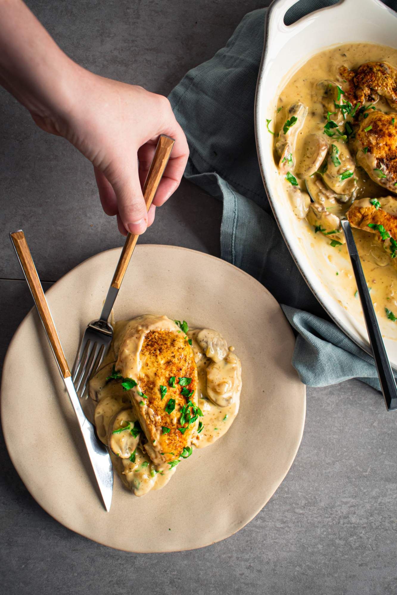 Chicken marsala cooked in the crockpot with a creamy mushroom sauce on a plate with a fork and knife.